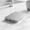 A silver power bank with a sleek design, featuring USB ports, resting on a marble surface.