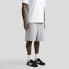 Grey shorts with a relaxed fit, paired with a white T-shirt and black sneakers. Features visible tattoos on the legs.