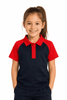 A girl smiles while wearing a navy blue and red polo shirt. The shirt features a logo on the front.