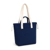 A navy tote bag with cream handles and a front pocket, featuring a logo on the side.