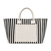 A striped tote bag in black and white with a plain cream-coloured front pocket and handles. It has a logo.