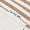 A close-up of a striped tote bag in cream and tan, featuring a label with branding.