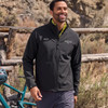 A unisex softshell jacket in black, featuring a logo, worn by a smiling individual outdoors.
