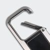 A silver metal carabiner with a curved hook and a small, detailed closure mechanism. It features a logo on one side.