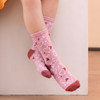 A pair of pink knitted kids' socks featuring heart patterns and a reddish band at the top, resting on a white surface.