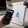 A white NFC A5 Smart Notebook features a logo, placed next to a smartphone and a laptop on a desk.