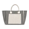 A striped tote bag in black and white with a plain cream-coloured front pocket and handles. It has a logo.