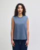 A sleeveless, boxy muscle t-shirt in a soft blue colour, featuring a rounded neckline and a logo.