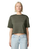 A woman wearing an olive green mid-length boxy top with short sleeves, paired with light blue jeans. The top features a logo.