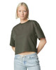 A women's mid-length boxy top in dark green, featuring a relaxed fit and short sleeves. The model is standing confidently.
