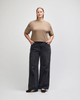 A mid-length boxy top in beige, worn with black wide-legged jeans. The top has a brand logo on it.