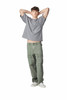 A model wearing a grey oversized boxy top and green cargo pants, with arms raised behind the head.