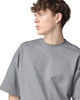 A grey unisex oversized boxy top with a round neckline and short sleeves, featuring a logo.