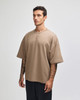 A beige oversized unisex boxy top with short sleeves and a simple design, featuring a logo.