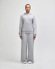 Grey wide-leg pants paired with a matching hoodie, featuring a logo, modelled by a standing woman.