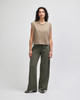 A model wearing a beige sleeveless top and olive green wide-leg pants, standing against a neutral background.