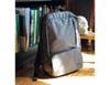 A grey backpack with multiple zippered compartments placed next to books and a decorative skull on a shelf.
