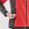 A red and black women's softshell jacket featuring zippered pockets and a logo on the lower side.