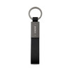 A black keytag with a metal rectangular attachment and a circular keyring. The product has a logo on the metal part.