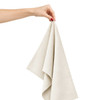 A hand holds a light beige cotton tea towel, showcasing its soft fabric and folded design.