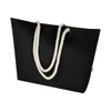 A black tote bag with thick white rope handles, featuring a logo on the side.