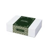 A white hamper box with a green decorative band featuring intricate patterns and a gift message.