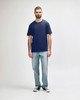 A man wearing a navy Gildan Softstyle adult midweight T-shirt and light blue jeans, standing against a plain background.