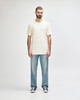 A white Gildan Softstyle adult T-shirt displayed on a model, paired with light blue jeans. The model stands against a neutral background.