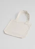 A cream canvas tote bag with two handles and a simple design. It has a visible logo on one side.