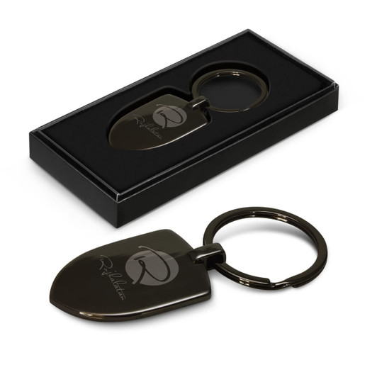 A black key ring shaped like a shovel, displayed in a black box, featuring a logo.