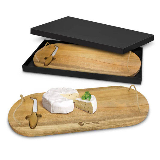 A wooden cheese board with a knife, featuring a round cheese piece and herbs, packaged in a black box.