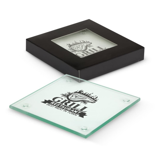 A square glass coaster, clear with a black base and branding, displayed in a black box.