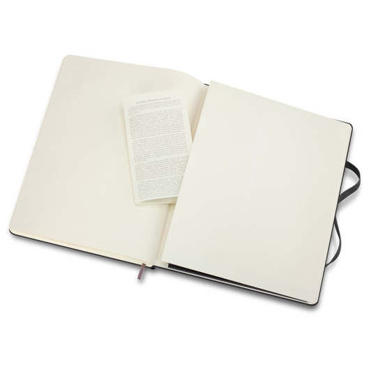 An extra-large Moleskine classic hard cover notebook in black, featuring plain cream pages and a ribbon bookmark.