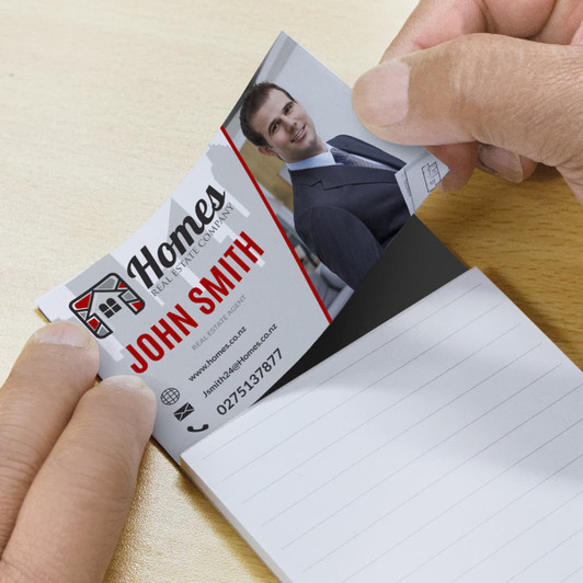 A magnet pad with lined pages being held, featuring a business card at the top. The pad has a black and white design.