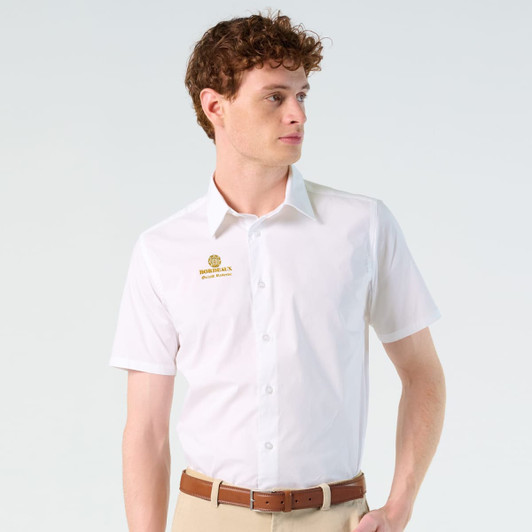 A short-sleeve white button-up shirt with a logo on the chest, worn by a model.