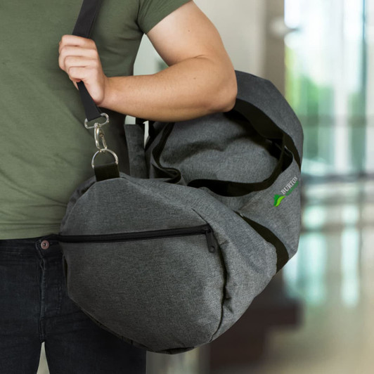 A grey Montreal Duffle Bag with a shoulder strap is being held by a person, featuring a logo and zippered pocket.