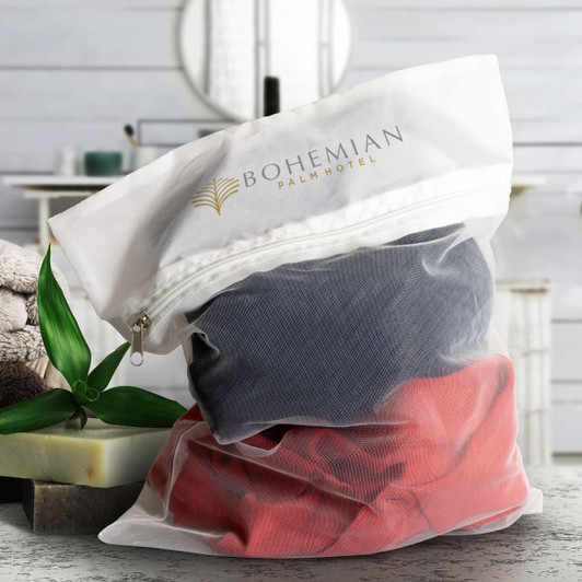 A mesh laundry bag with grey and red clothing inside, featuring a logo on the top.