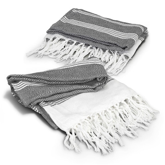 A grey and white Ohau Throw Blanket with tasselled edges, featuring a geometric pattern. It has a branding logo.