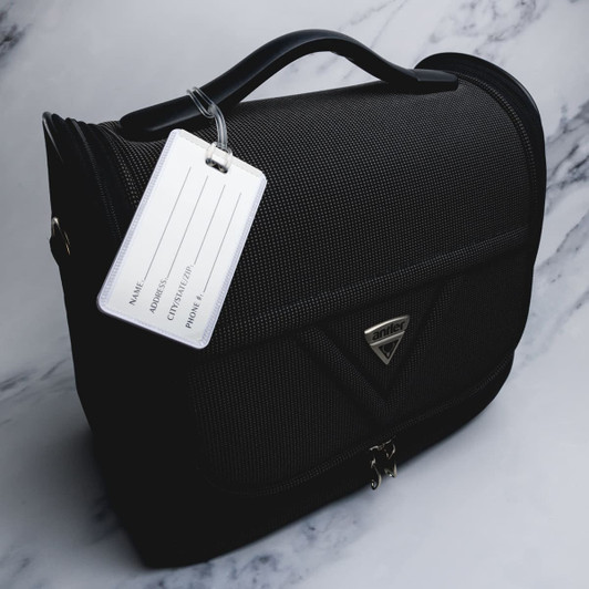 A black luggage tag attached to a stylish black bag, featuring a logo and an empty information panel.