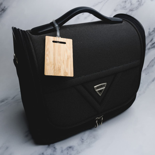 A black luggage bag with a bamboo luggage tag attached, featuring a logo on the front.
