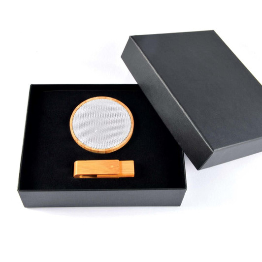 A sleek gift box containing a bamboo wireless speaker and a matching bamboo phone stand.