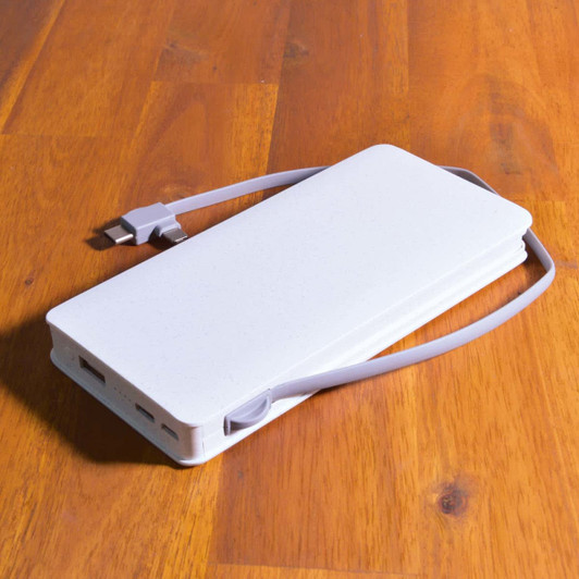 A wireless power bank in a sleek white design, featuring multiple USB ports and a grey charging cable attached.