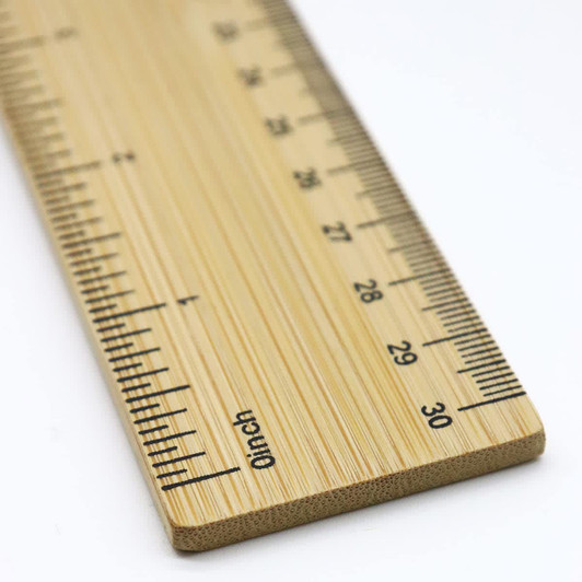 A bamboo ruler featuring a clear measurement scale in inches, showcasing a natural wood finish and a branding logo.