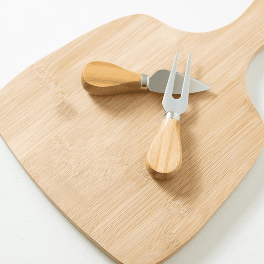 A bamboo cheese board with two stainless steel knives featuring light wooden handles.