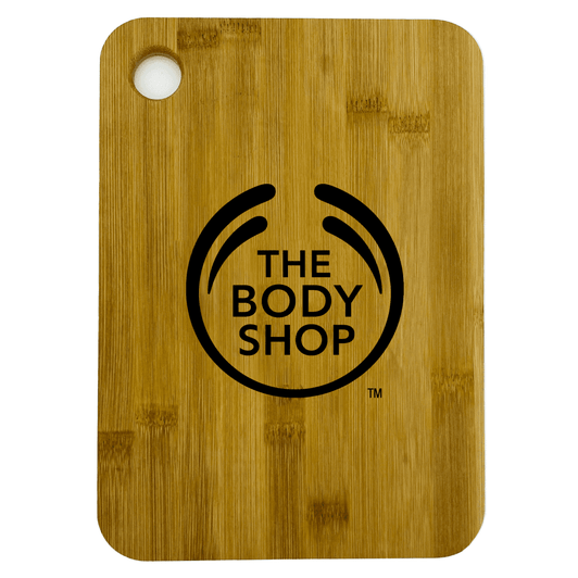 A large bamboo cutting board with rounded corners, featuring a logo on the surface.
