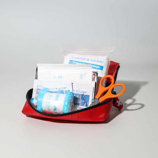 A red first aid travel kit with orange scissors and various medical supplies visible inside.