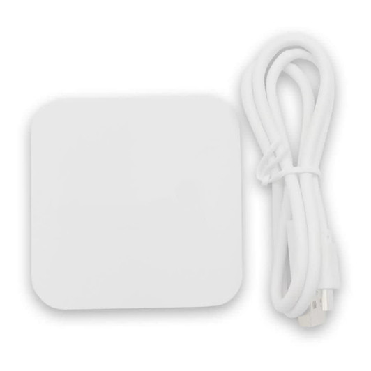 A white wireless charging dock with a white USB cable beside it, designed for phone charging.