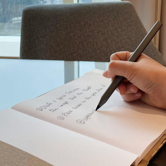 A grey metal pen rests on a page of a notebook, with handwritten notes beside it.