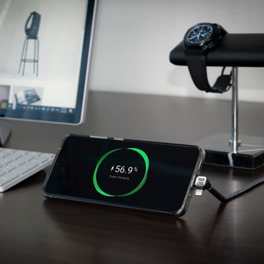 A charging smartphone displaying a battery percentage, connected to a Trident Pro Eco Superfast Charge Cable on a desk.