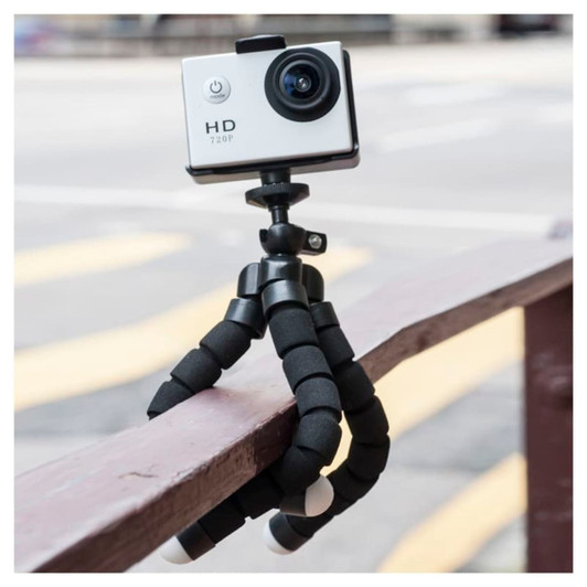 A flexible black tripod with a small white camera attached, resting on a wooden railing.